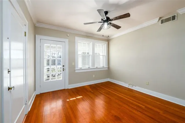 a view of empty room with wooden floor and fan