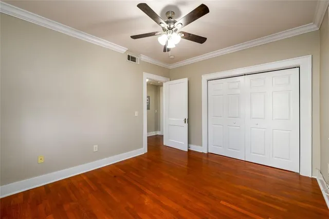 an empty room with wooden floor and ceiling fan