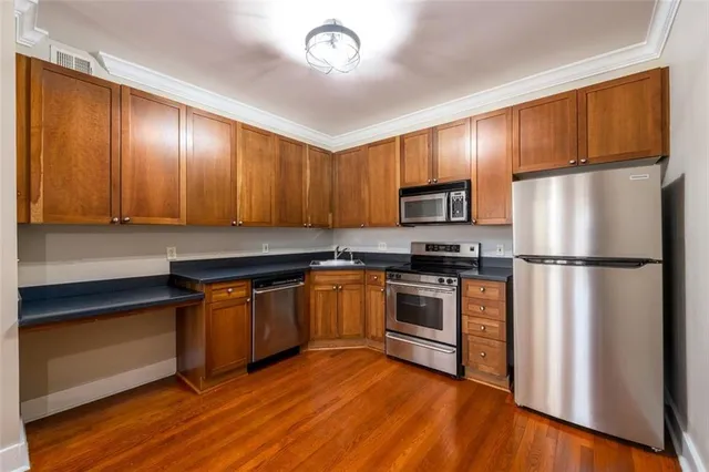 a kitchen with granite countertop wooden floors stainless steel appliances and cabinets