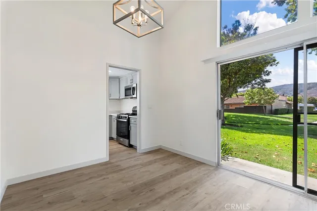 a view of an empty room with wooden floor and kitchen