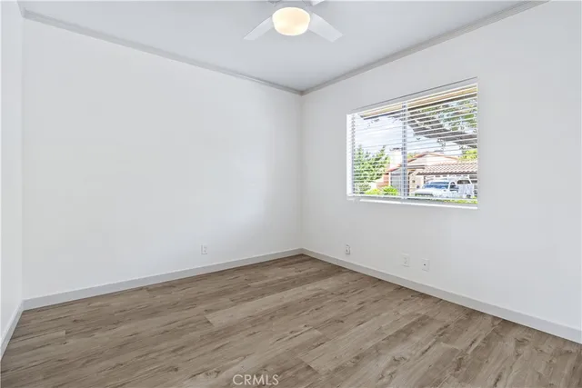 a view of an empty room with a window and wooden floor