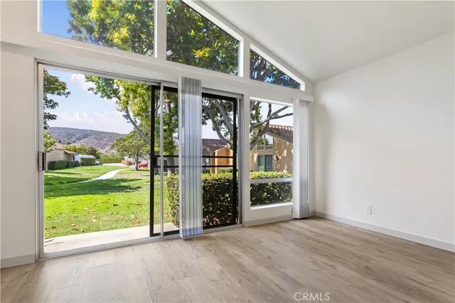 a view of an empty room with wooden floor and a fireplace