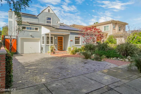 a front view of a house with a yard and potted plants