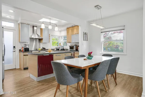 a dining room with kitchen island stainless steel appliances furniture a chandelier open kitchen view and a chandelier