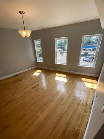 a view of an empty room with window and wooden floor