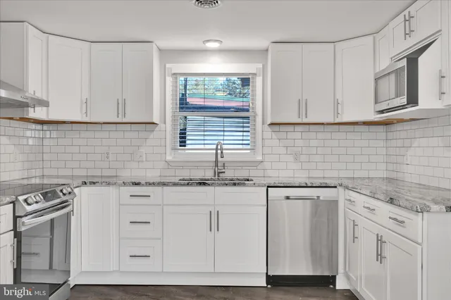 a kitchen with granite countertop white cabinets and white appliances