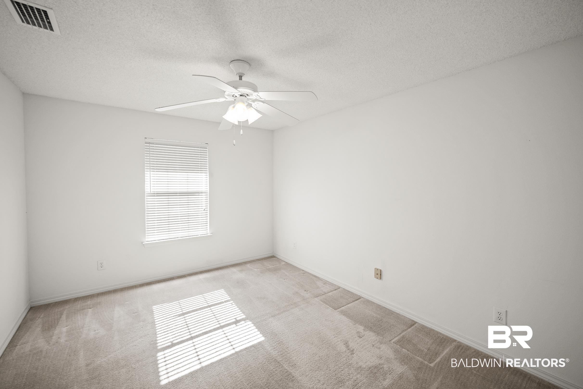 323 Manchester Lane Foley, AL 36535 - Photo 18 of 30 Neutral tone-on-tone carpeting complements the white walls and ceiling in this room featuring a window with horizontal blinds and a ceiling fan with integrated lighting
