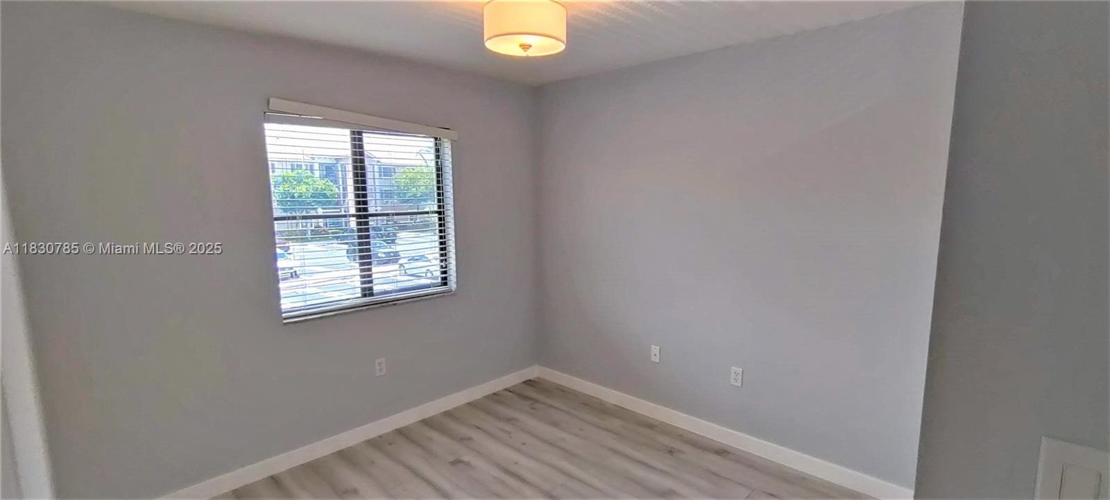 22911 Southwest 88th Place, Unit 721 Cutler Bay, FL 33190 - Photo 12 of 20 a view of an empty room with wooden floor and a window