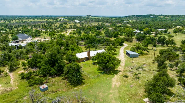 an aerial view of residential houses with outdoor space and trees