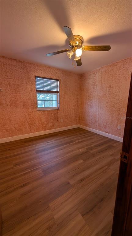 607 Gaul Way Kissimmee, FL 34759 - Photo 28 of 30 an empty room with wooden floor chandelier fan and windows