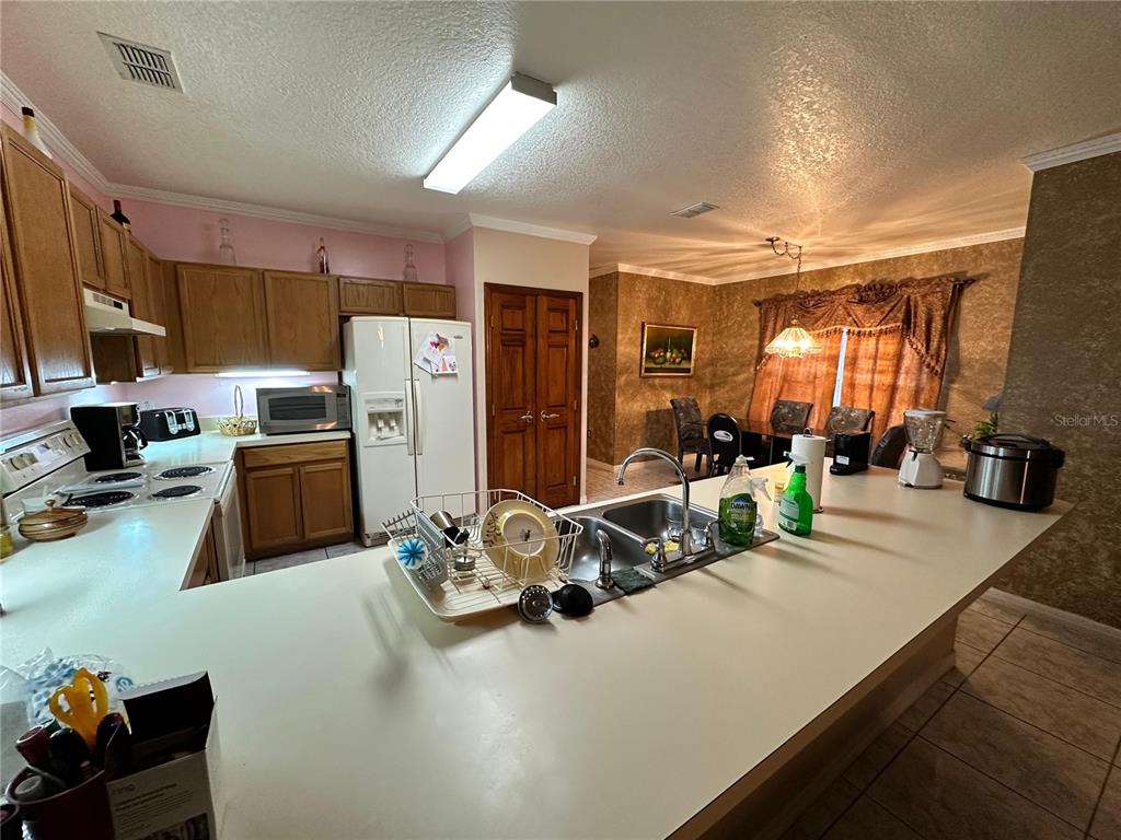 607 Gaul Way Kissimmee, FL 34759 - Photo 10 of 30 a kitchen with stainless steel appliances a sink a stove a refrigerator a washer dryer and a refrigerator