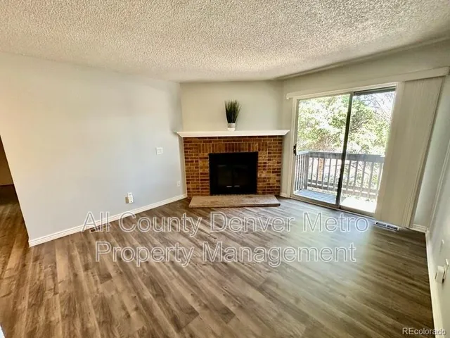 an empty room with wooden floor fireplace and windows
