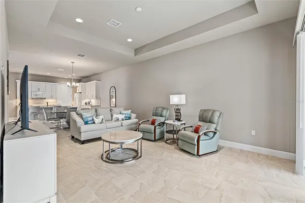 a living room with furniture a flat screen tv and kitchen view