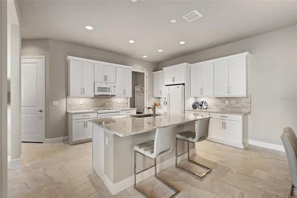 a kitchen with white cabinets and sink