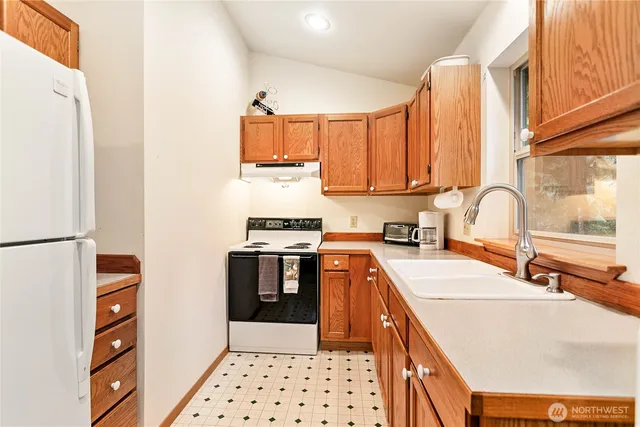 a kitchen with stainless steel appliances a sink a stove a refrigerator cabinets and a window