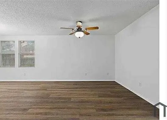 a view of a room with wooden floor and a ceiling fan