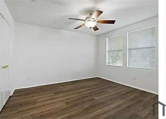 a view of a big room with wooden floor and windows