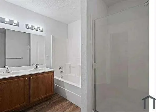 a spacious bathroom with a double vanity sink a mirror and a bathtub