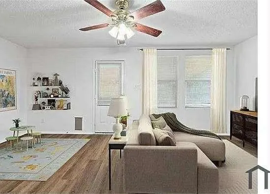 a living room with furniture two window and a flat screen tv