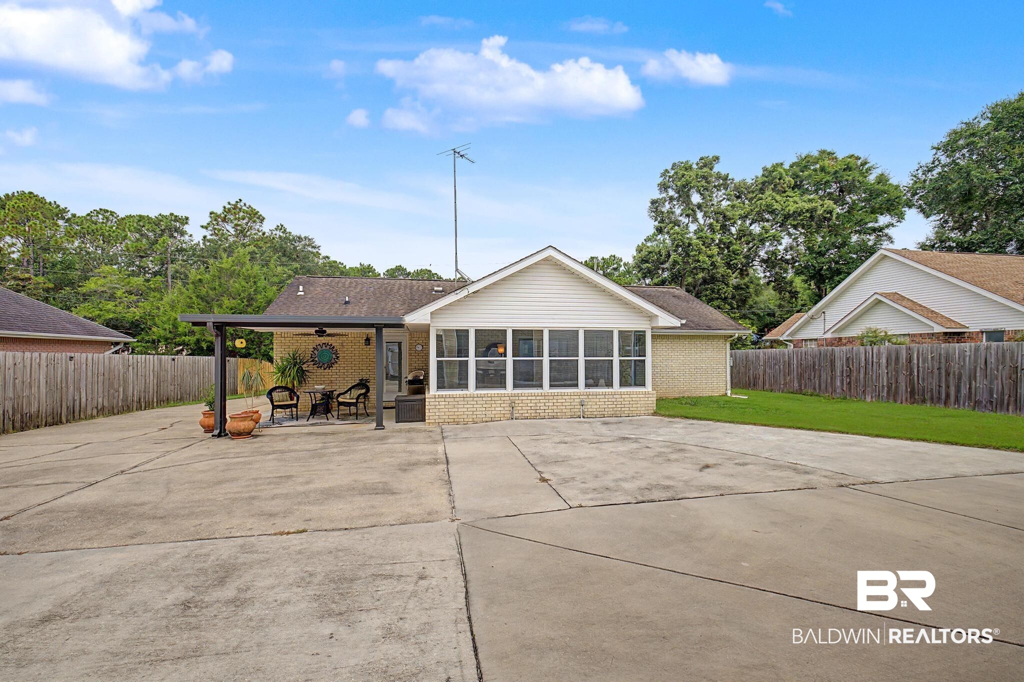 2808 Pine Ridge Drive Lillian, AL 36549 - Photo 28 of 47 Rear exterior featuring an attached covered patio with a ceiling fan, a sunroom with multiple windows, and a brick facade