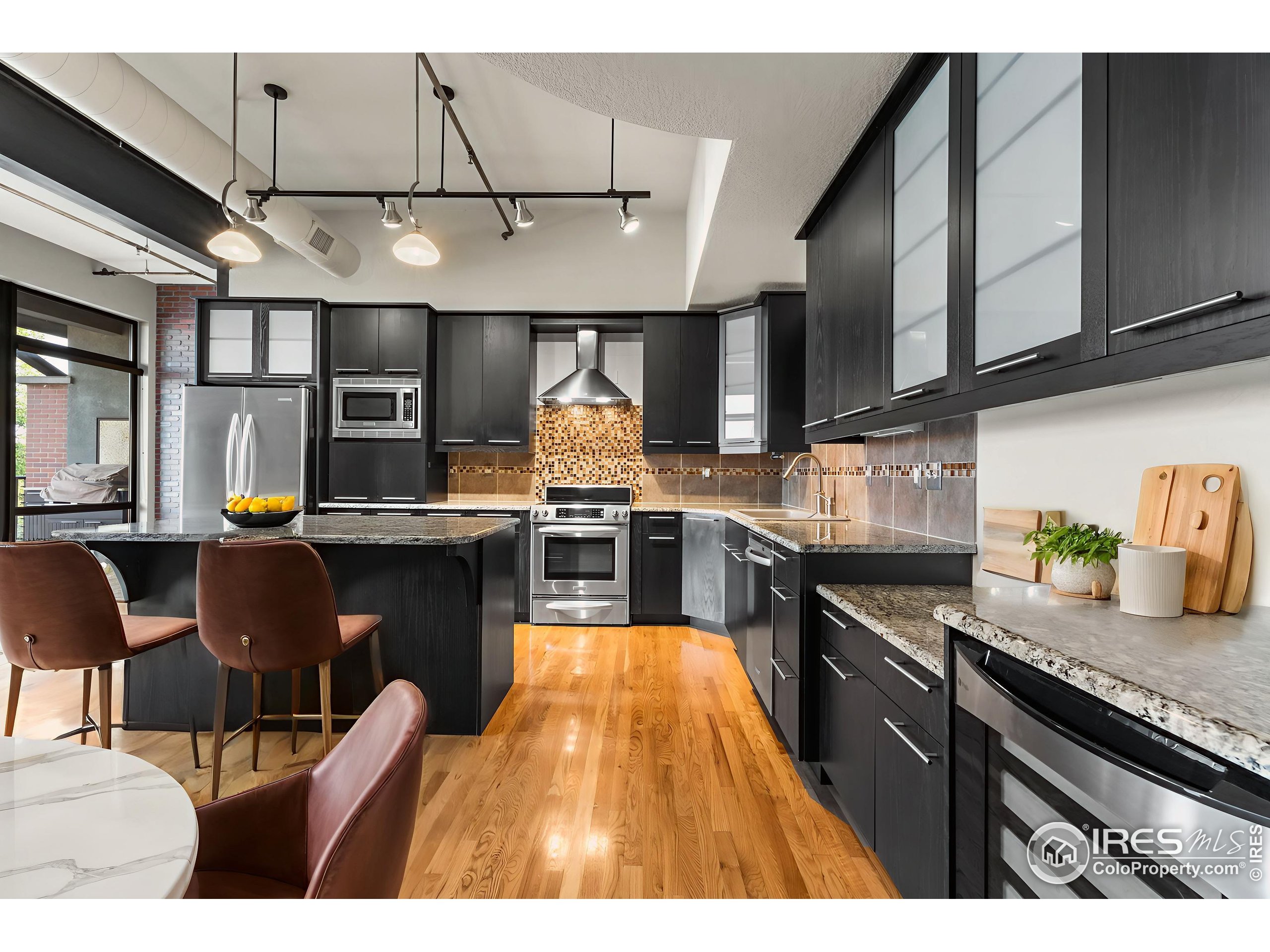 210 West Magnolia Street, Unit 320 Fort Collins, CO 80521 - Photo 11 of 45 a open kitchen with stainless steel appliances granite countertop a stove top oven a sink dishwasher and cabinets with wooden floor