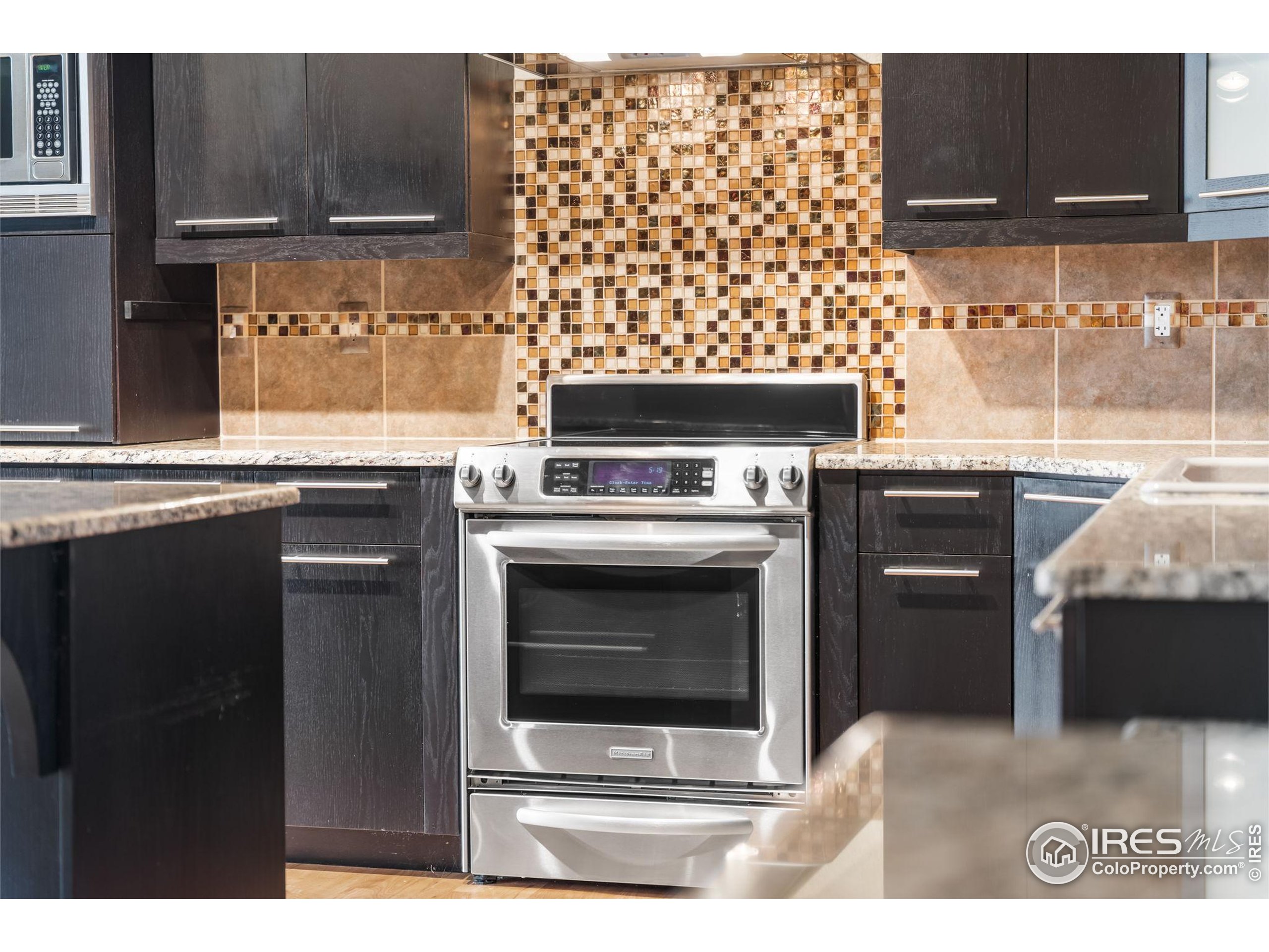 210 West Magnolia Street, Unit 320 Fort Collins, CO 80521 - Photo 14 of 45 a kitchen with granite countertop a stove top oven microwave and cabinets