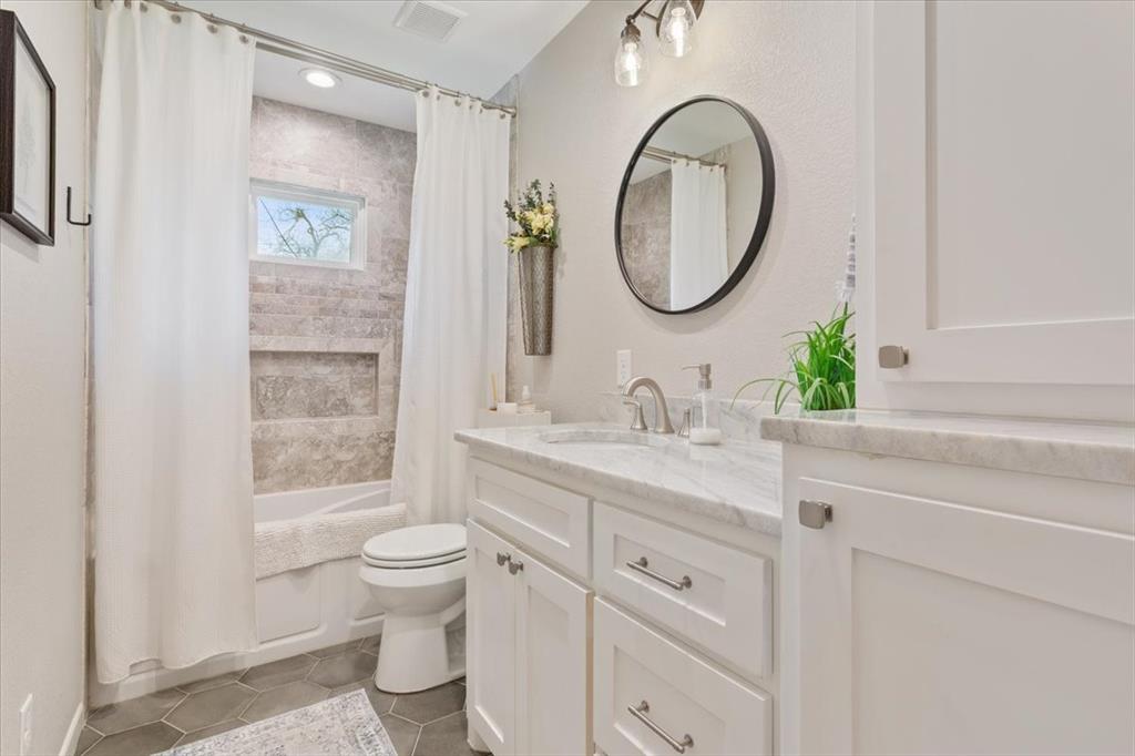 2209 North 52nd Street Waco, TX 76710 - Photo 25 of 34 a bathroom with a granite countertop toilet a sink a mirror and a window