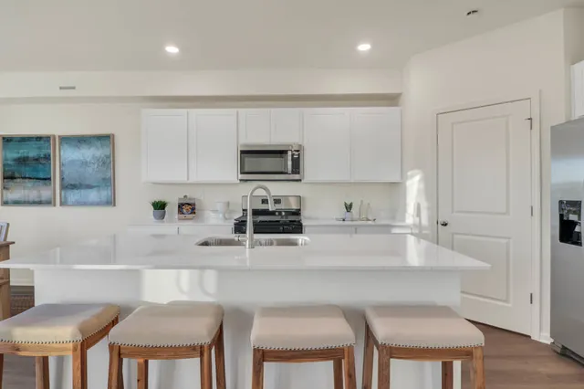 a kitchen with stainless steel appliances a stove a sink a table and chairs