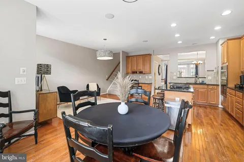 a kitchen with stainless steel appliances granite countertop a refrigerator a stove a sink a dining table and chairs with wooden floor