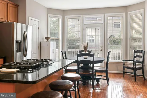 a kitchen with stainless steel appliances granite countertop a stove top oven a dining table and chairs with wooden floor