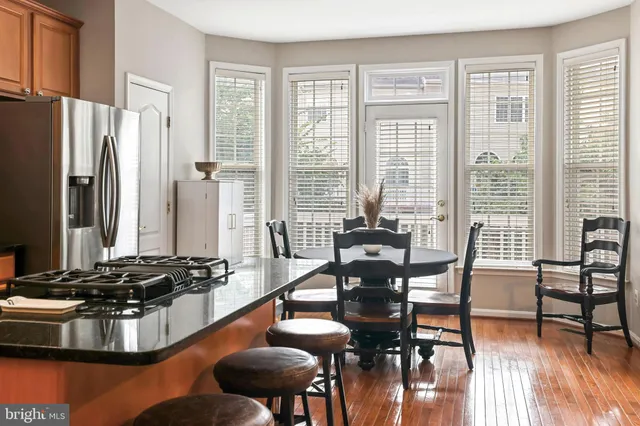 a kitchen with stainless steel appliances granite countertop a stove top oven a dining table and chairs with wooden floor