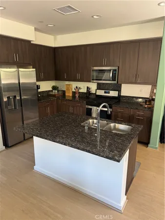 a kitchen with stainless steel appliances granite countertop a sink a stove and a microwave with wooden floor