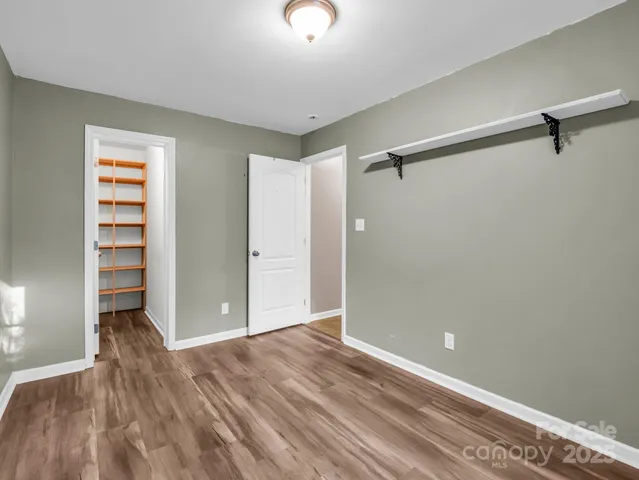 a view of room with walk in closet and wooden floor