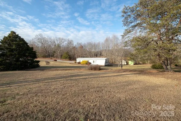 a view of dirt field with large trees