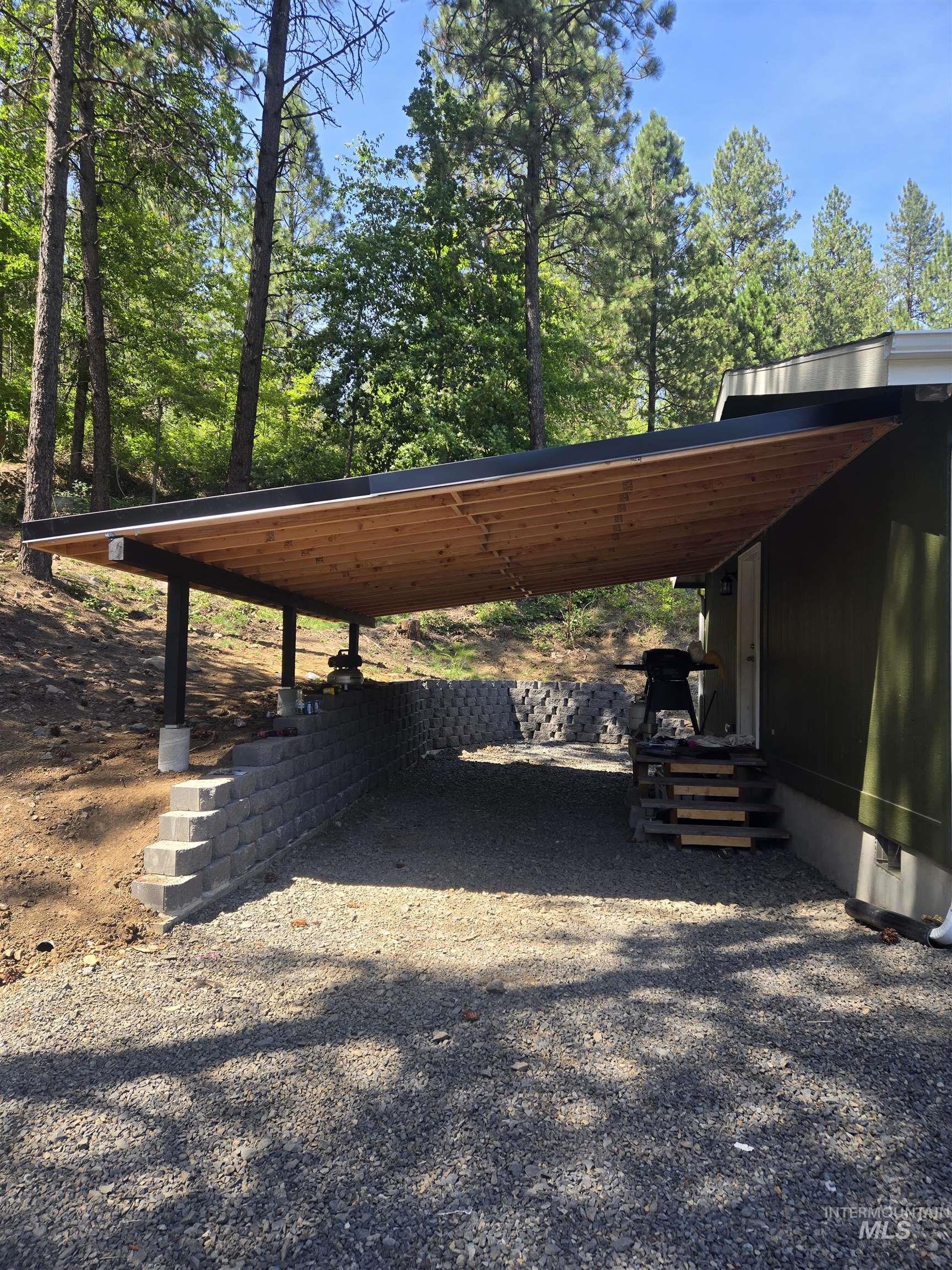 174 Konkolville Road Orofino, ID 83544 - Photo 37 of 45 Carport featuring a wood-panel ceiling, dark support beams, and gravel surfacing