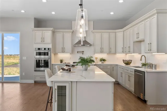 a kitchen with stainless steel appliances kitchen island granite countertop a sink dishwasher a stove a refrigerator and white cabinets with wooden floor