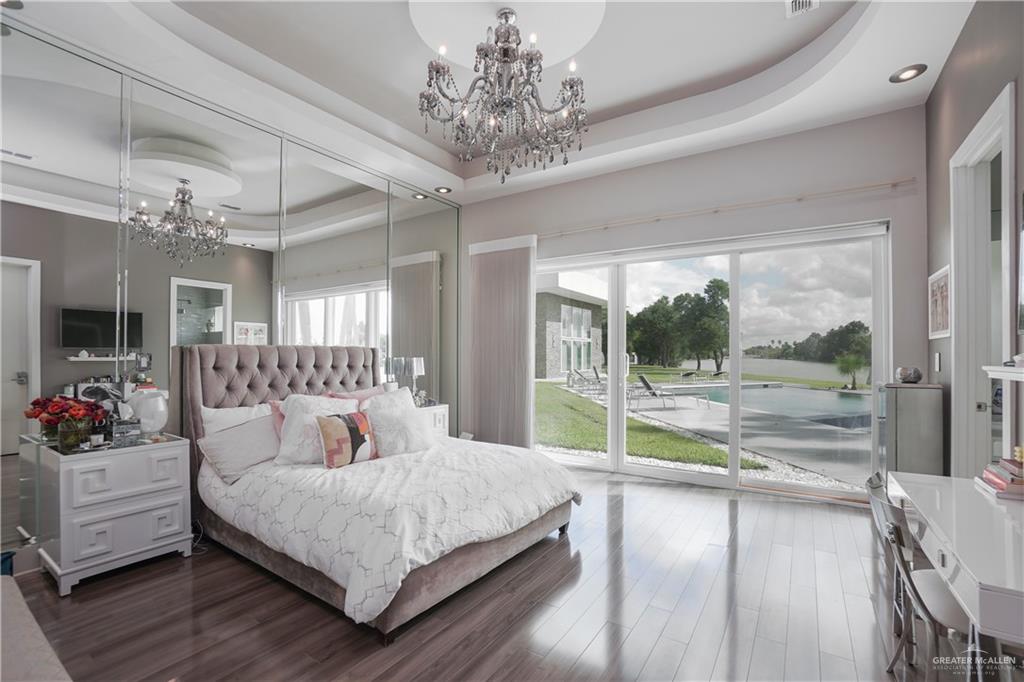 1500 Coffee Port Road Brownsville, TX 78521 - Photo 16 of 42 a bedroom with a large bed and a chandelier
