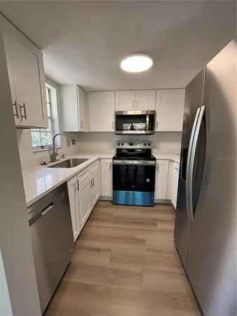 a kitchen with stainless steel appliances granite countertop a sink stove refrigerator and cabinets