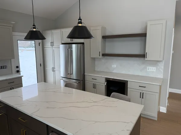a kitchen with stainless steel appliances a kitchen island a stove a refrigerator a sink and a fireplace