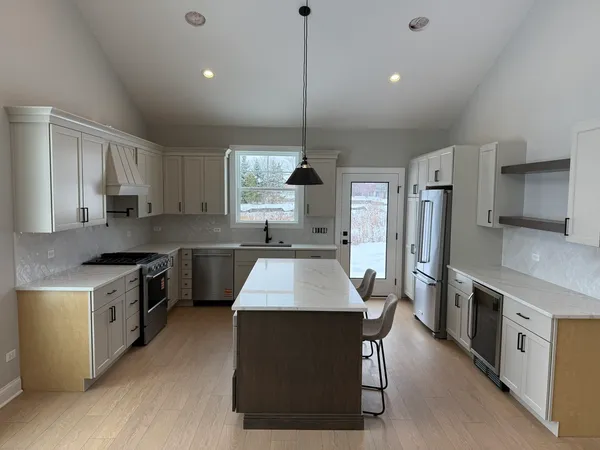 a kitchen with kitchen island a counter top space a sink stainless steel appliances and cabinets