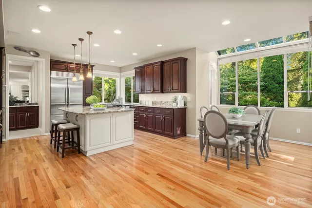 a living room with stainless steel appliances granite countertop furniture wooden floor and a kitchen view