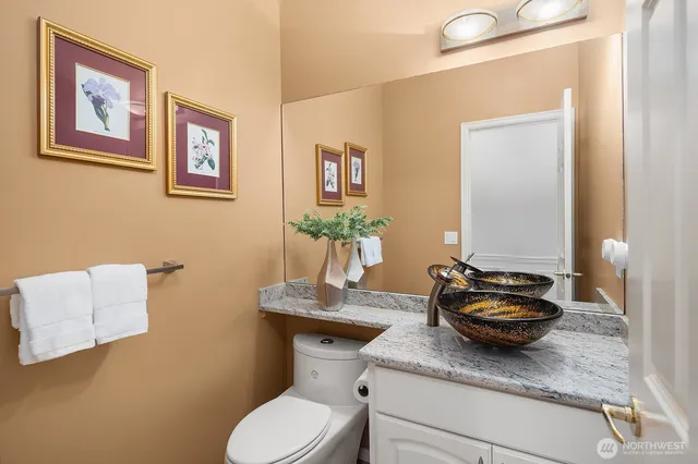 a bathroom with a granite countertop toilet sink and mirror