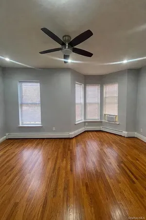 a view of empty room with wooden floor and fan