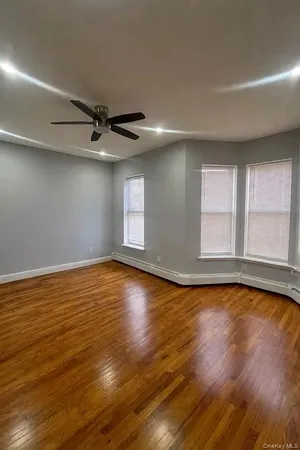 a view of an empty room with window and wooden floor