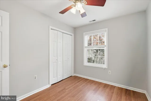 an empty room with wooden floor chandelier and windows