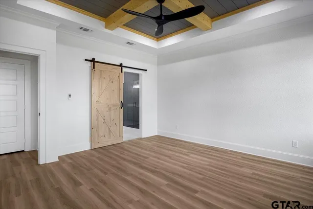 an empty room with wooden floor chandelier fan and windows