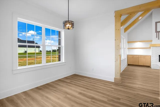 a view of an empty room with wooden floor and windows
