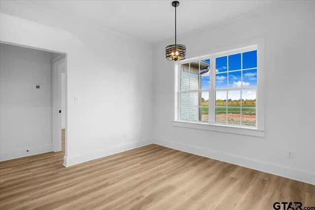 a view of an empty room with wooden floor fireplace and a window