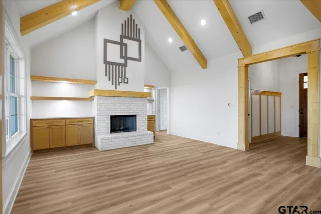 an empty room with windows and fireplace