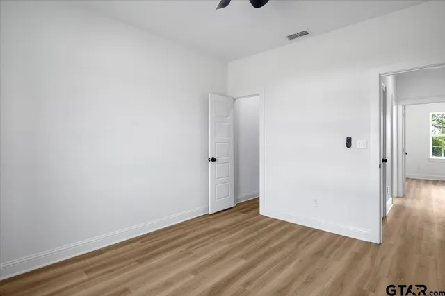a view of an empty room with wooden floor and closet